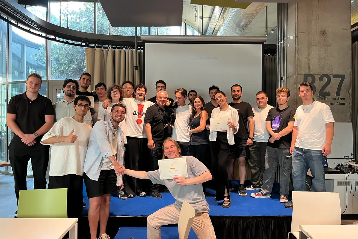 Participants of the July 2026 AI prototyping hackathon presenting at a whiteboard at ÖzÜ-X